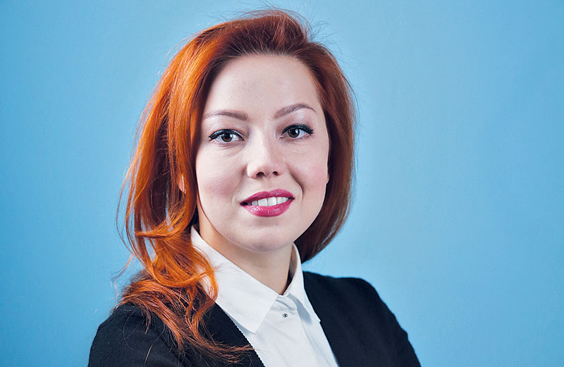 Young smiling Ukrainian woman with red hair in black blazer and white collared shirt