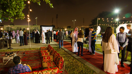 Saudi professionals standing around conversing in small groups in an outdoor patio 