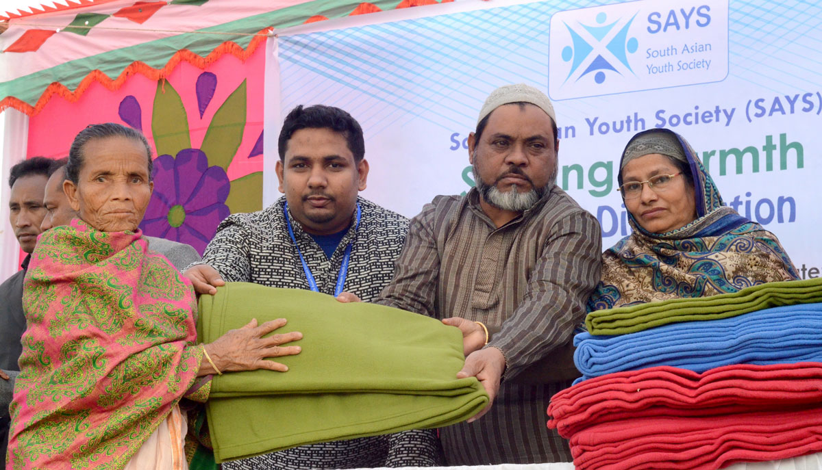 Young man holds blankets standing with group of older people