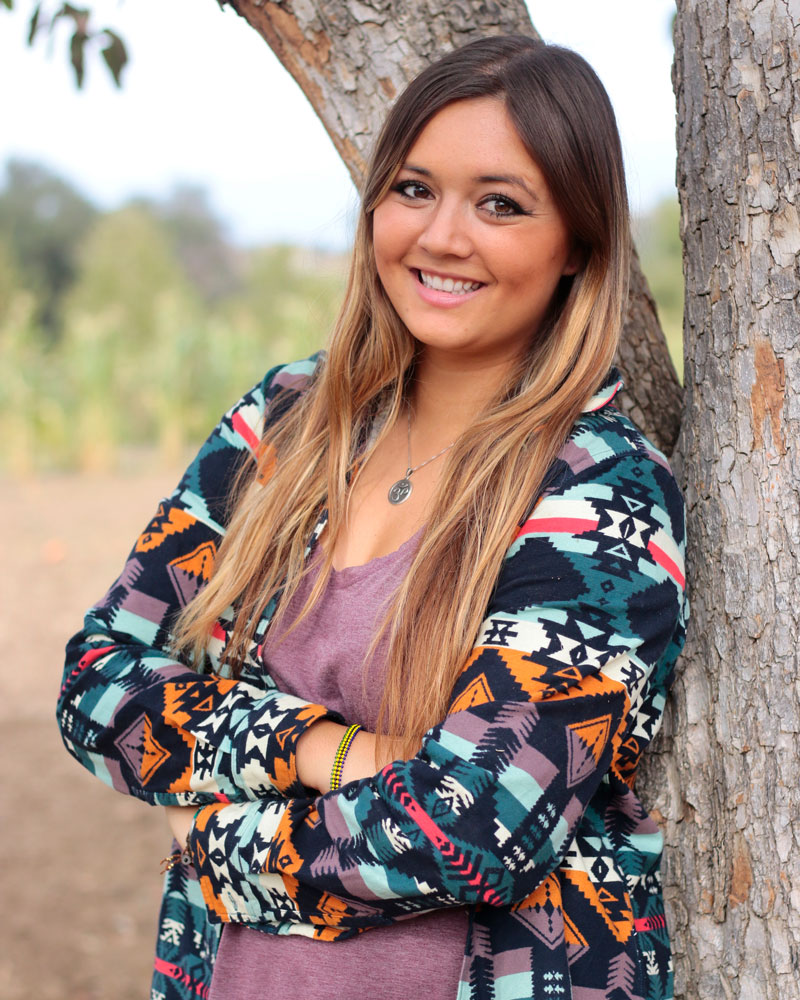 Young woman leaning against a tree and smiling