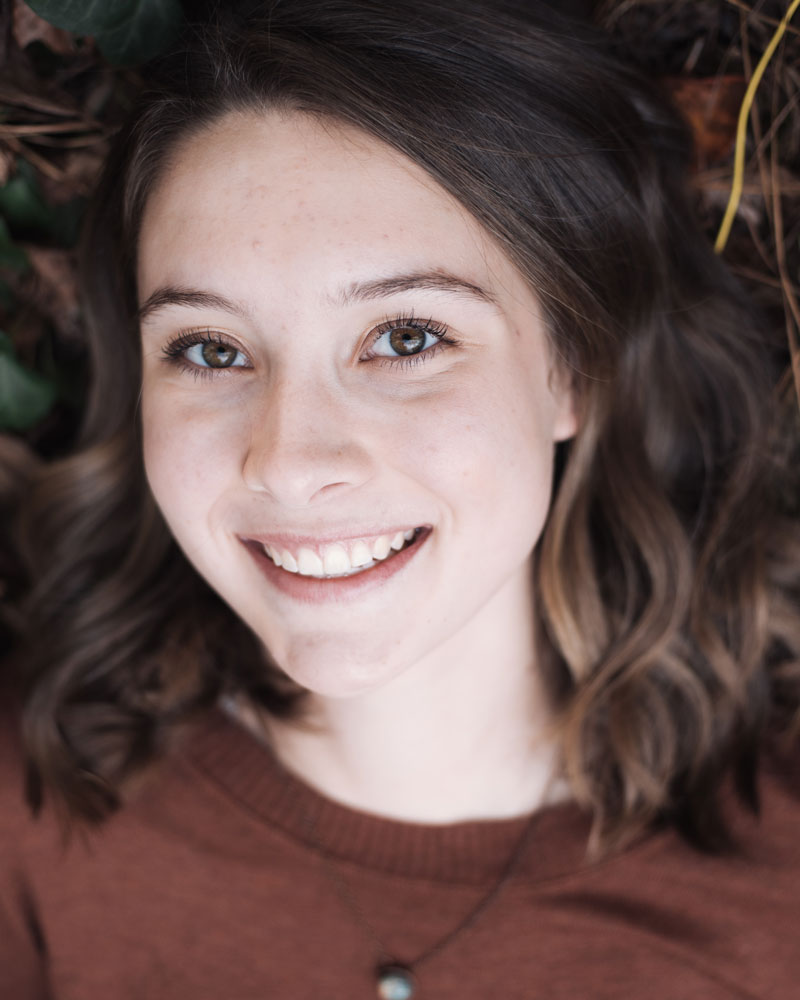 Young woman laying on a bed of leaves and smiling