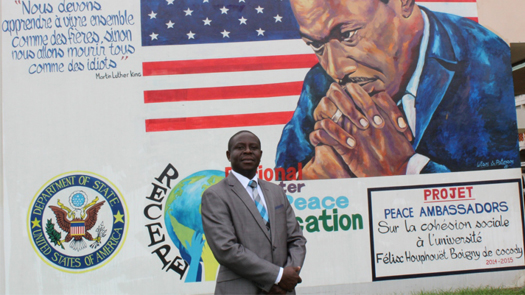 Kouadjo Hilaire, Associate Professor at University of Cocody, Abidjan, standing in front of a mural