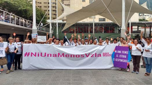 Women holding a large banner that reads "#NiUnaMenosVzla" marching against gender-based violence Women holding a large banner that reads "#NiUnaMenosVzla" marching against gender-based violence