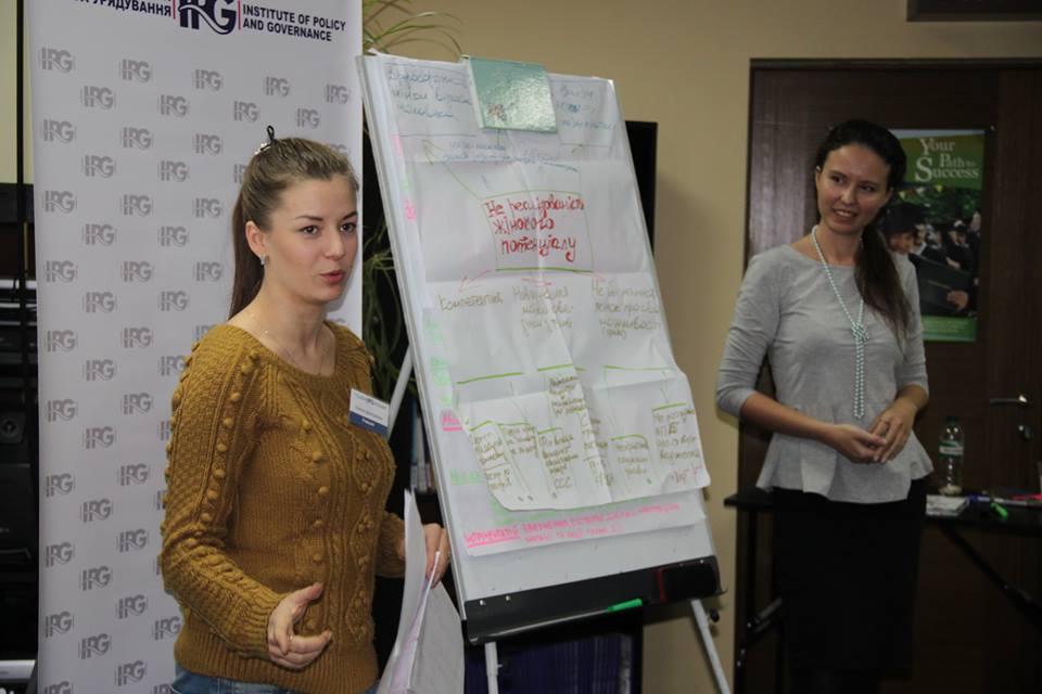 Two women stand beside an easel appearing to be giving a presentation