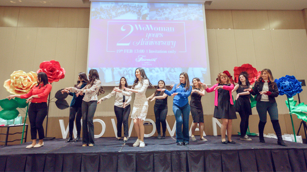 Women dancing on a stage in front of a projector screen.
