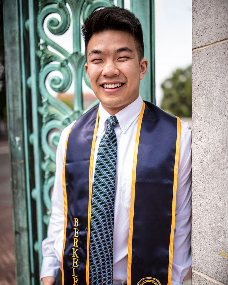 Young man wearing college sash around his neck smiling