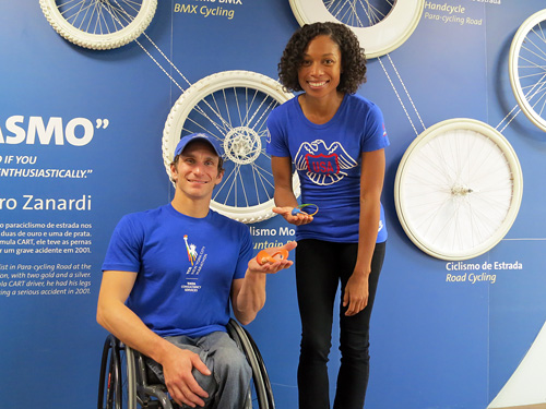 Josh George poses with fellow Sports Envoy Allyson Felix in front of a cycling exhibit