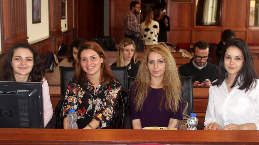 Four young women sitting at a desk in a court room