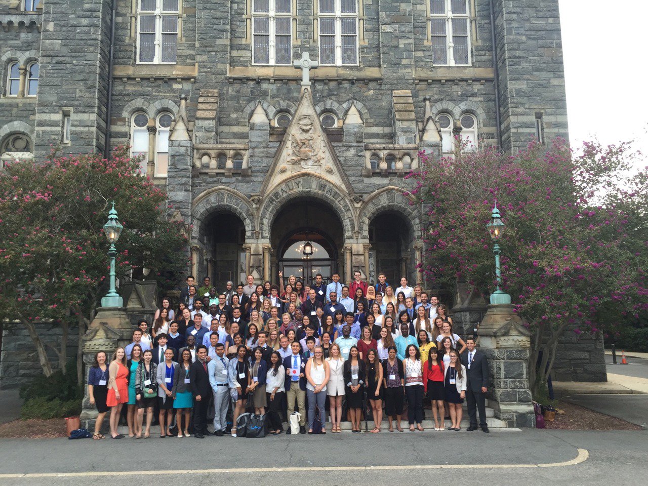 Group of students pose in front of stately academic building