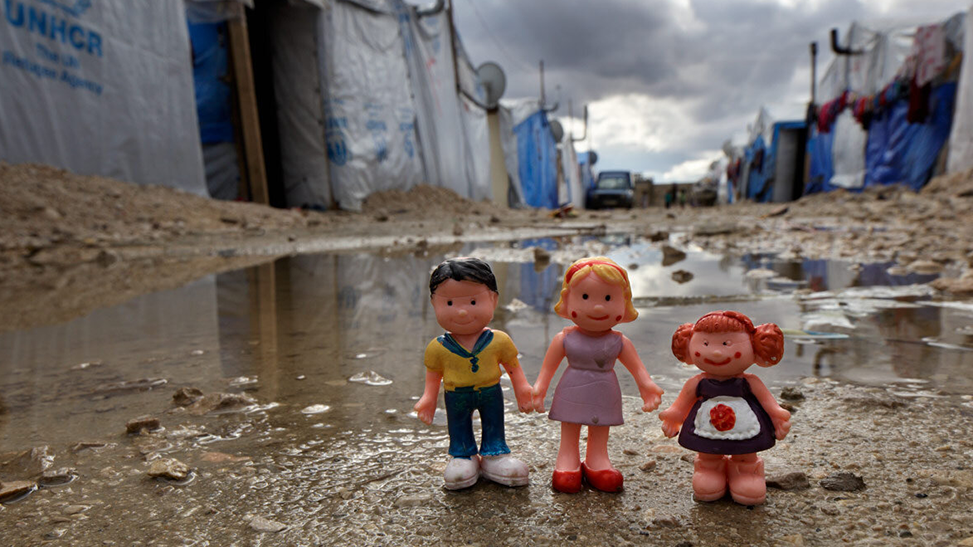 Three dolls holding hands in refugee camp