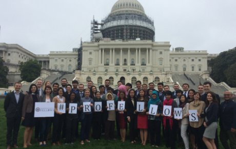 People posing in front of the U.S. Capitol building holding signs that spell out "#PROFELLOWS"