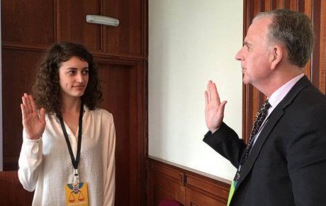 Young girl raising her right hand in front of man also raising his right hand