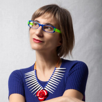 Woman wearing colorful glasses looks off to the right with a slight smile