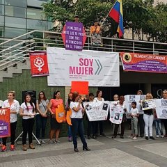 Woman talking on a microphone in a town square advocating against gender-based violence.