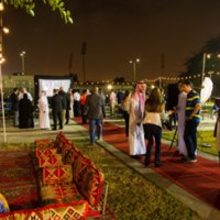 Saudi professionals standing around conversing in small groups in an outdoor patio