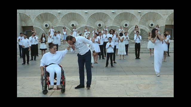 Man kisses the hand of a woman in a wheel chair