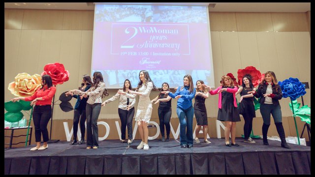 Women dancing on a stage in front of a projector screen.