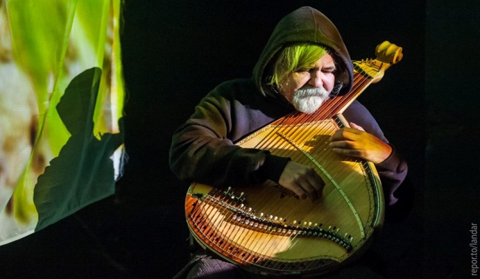 Older man playing a lute-like instrument